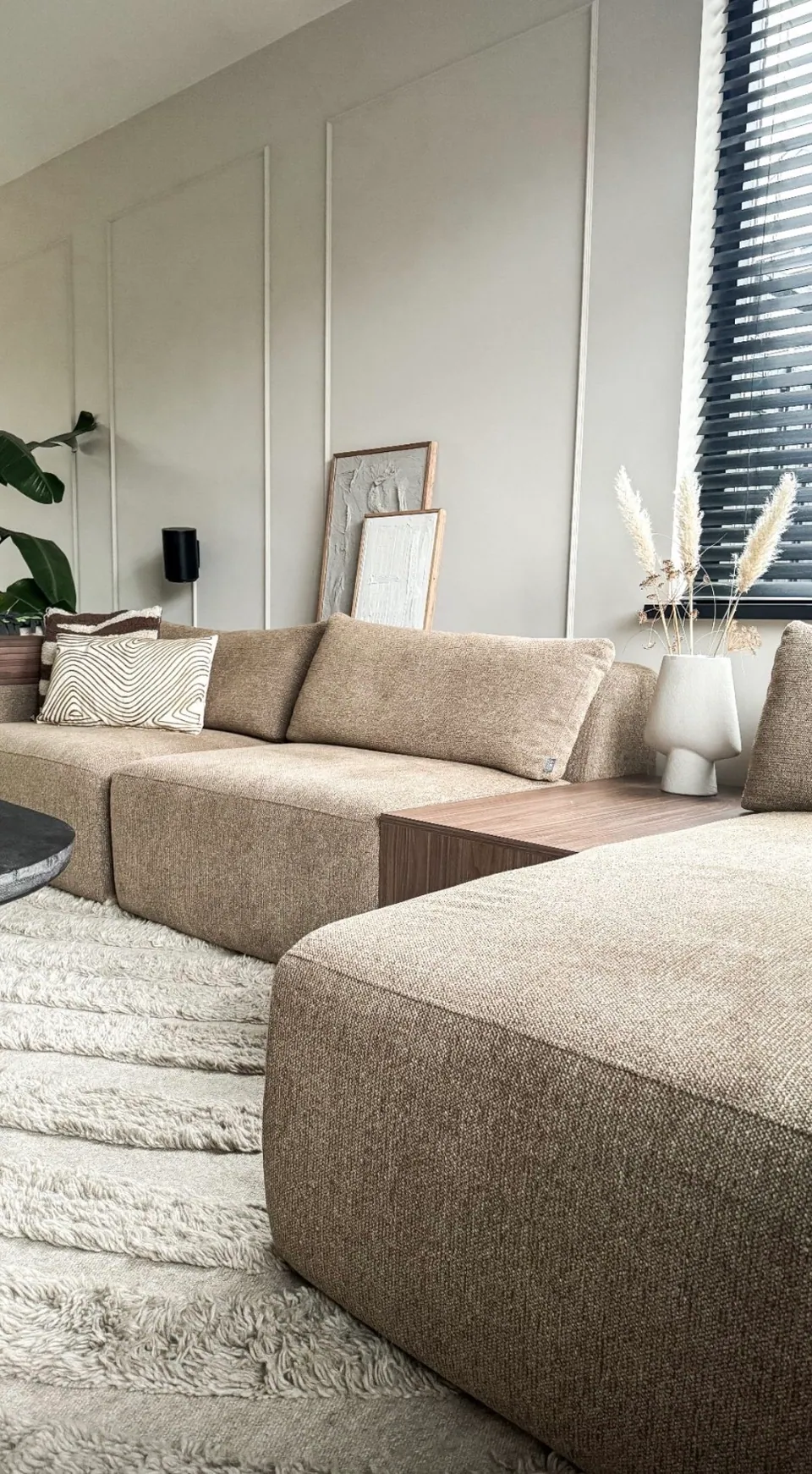 Beige bank met wollen vloerkleed in een rustige woonkamer
